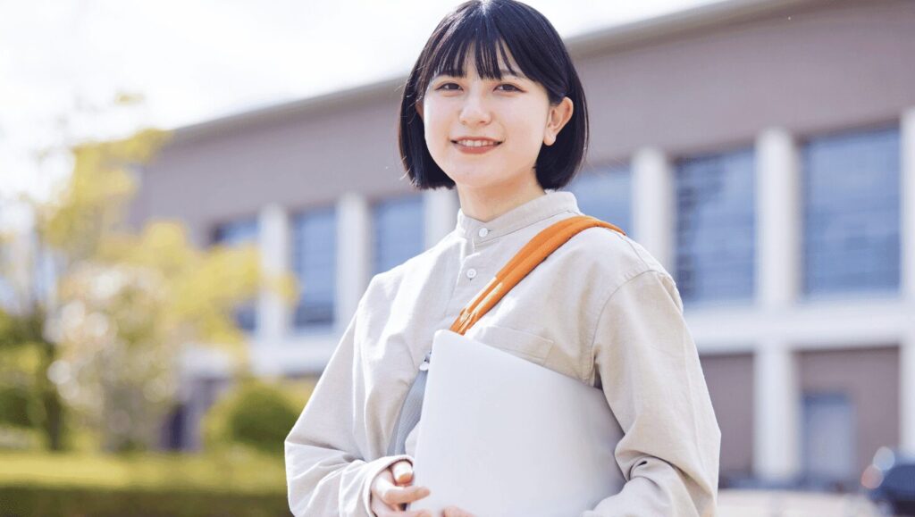 ノートパソコンを持って笑顔の女子大学生